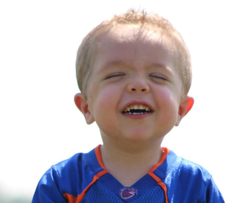 A young boy wearing a blue and orange football jersey.