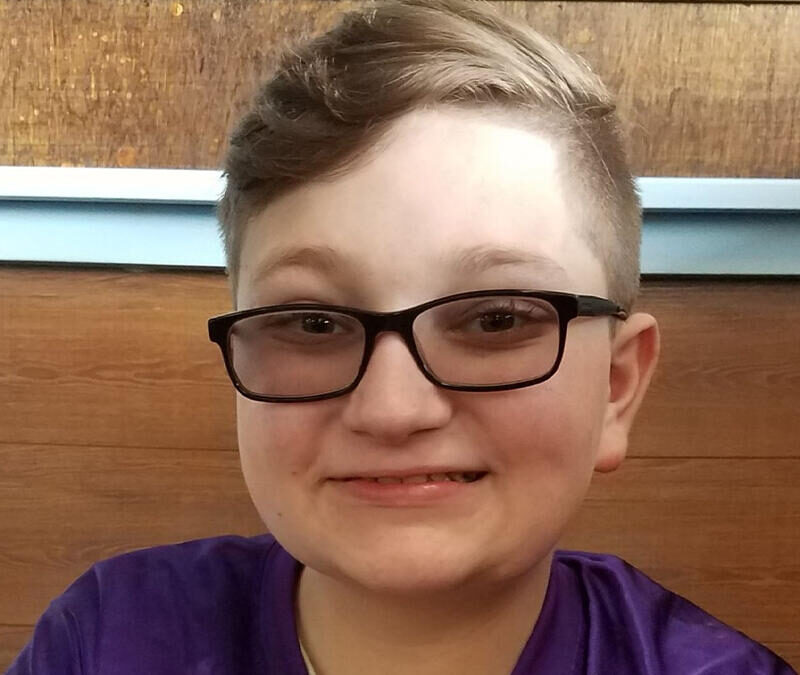 A young boy wearing glasses and a purple shirt.