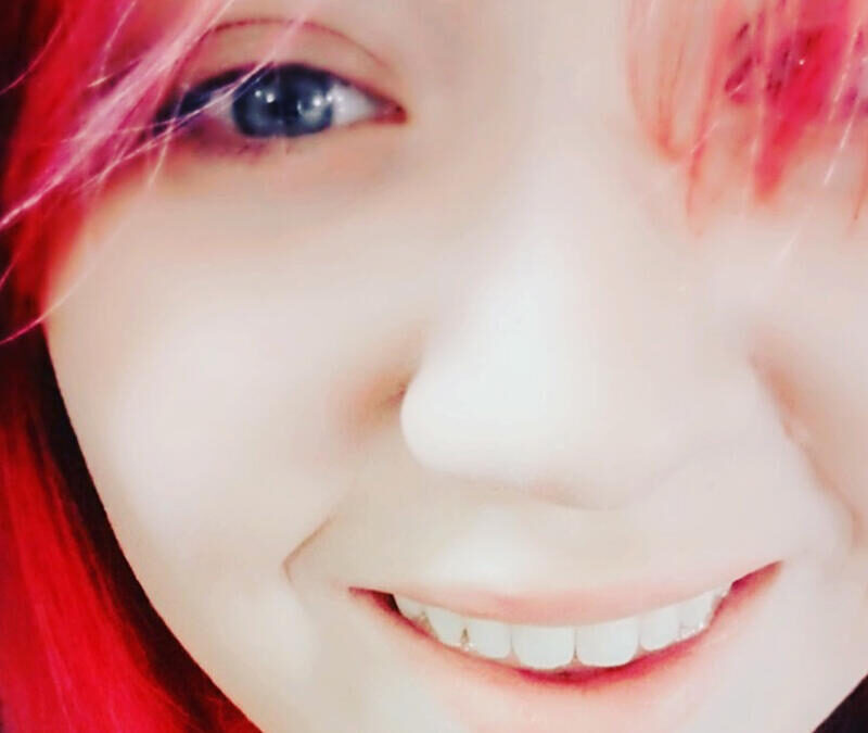 A girl with red hair is smiling at the camera.
