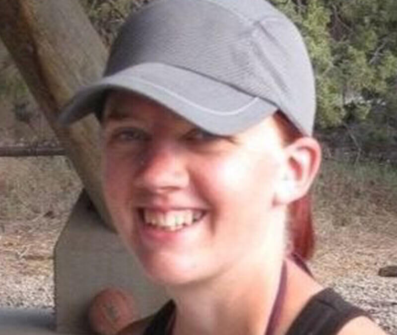 A woman wearing a baseball cap smiles for the camera.