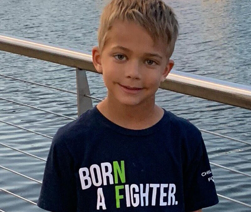 A young boy wearing a t - shirt that says born a fighter.