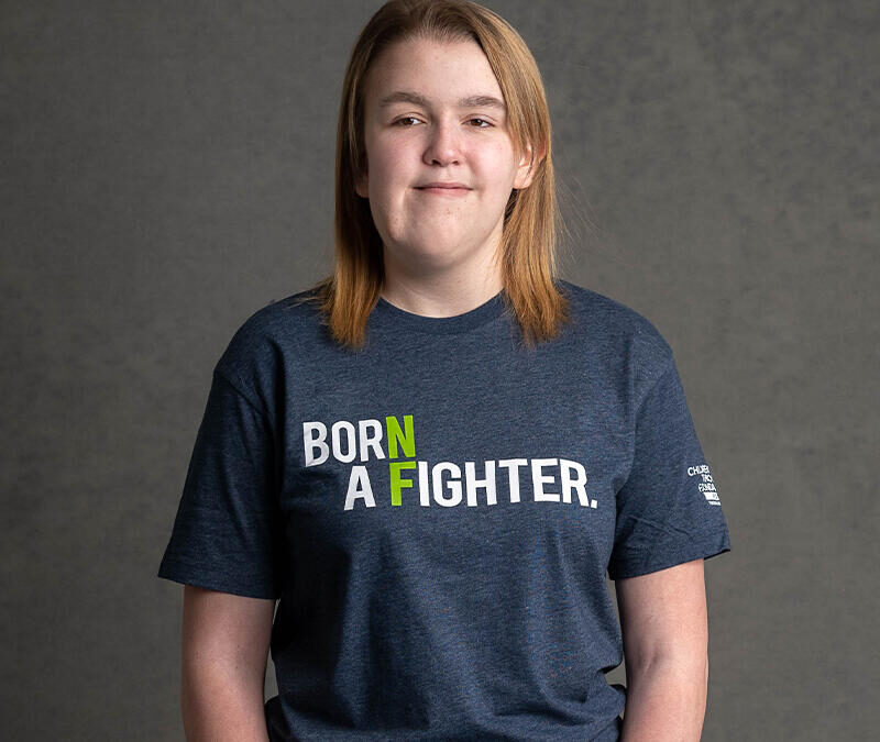 A girl wearing a t - shirt that says born a fighter.