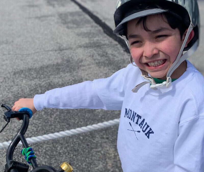 A young boy smiles while riding his bike.