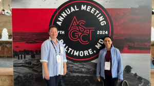 Two individuals standing in front of a banner for the "ASGCT 2024 Annual Meeting" in Baltimore, smiling at the camera.