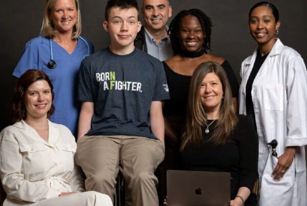 A group of seven diverse people, including medical professionals, a young person in a "Born a Fighter" shirt, and others, pose together for the 2023 Children's Tumor Foundation Annual Report cover.