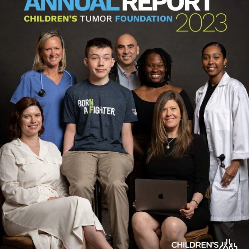 A group of seven diverse people, including medical professionals, a young person in a "Born a Fighter" shirt, and others, pose together for the 2023 Children's Tumor Foundation Annual Report cover.