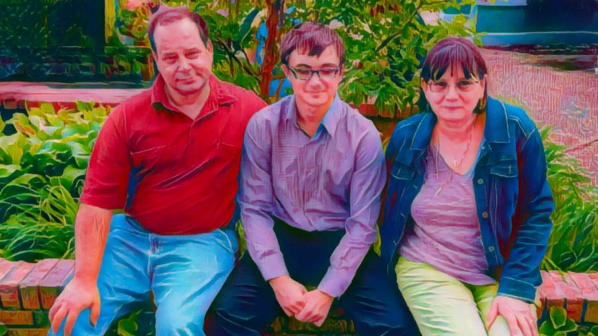 Three people sitting on a brick ledge in a garden, with plants in the background.