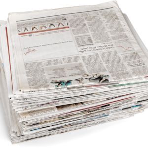 A stack of newspapers piled neatly on a surface.