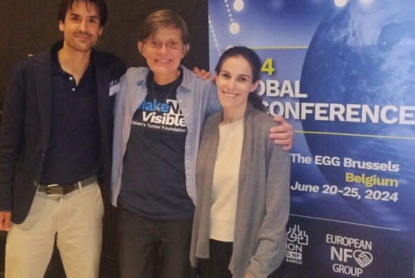 Three people smiling and posing in front of a banner for the 2024 Global Conference, held in Brussels from June 20-25, 2024.